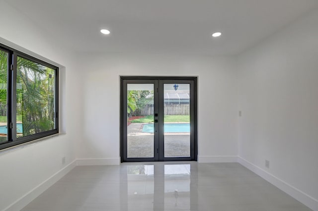 tiled spare room featuring french doors and a wealth of natural light