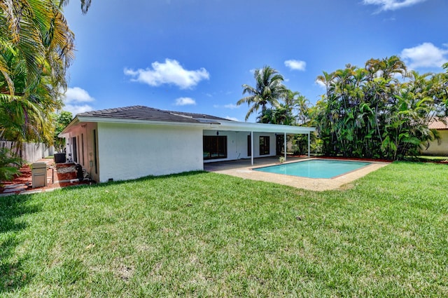 rear view of property with a lawn, a patio area, and a fenced in pool