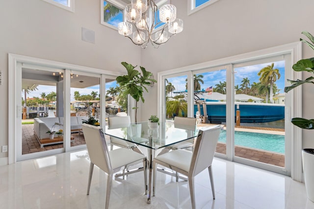 tiled dining room featuring a healthy amount of sunlight, a towering ceiling, and an inviting chandelier