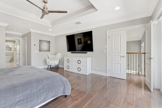 bedroom featuring a tray ceiling, ceiling fan, hardwood / wood-style flooring, crown molding, and ensuite bathroom