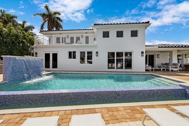 view of swimming pool with a patio area, pool water feature, and french doors