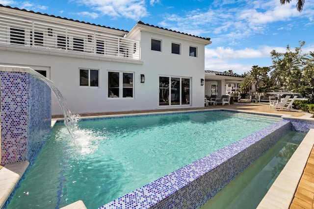 view of pool with pool water feature and a patio