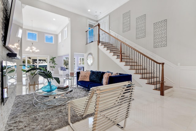 living room featuring a notable chandelier, ornamental molding, light tile floors, and a towering ceiling