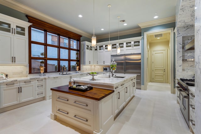 kitchen with tasteful backsplash, pendant lighting, an island with sink, and stainless steel stove