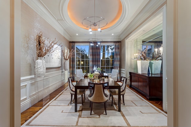 dining space with a tray ceiling, crown molding, and a notable chandelier