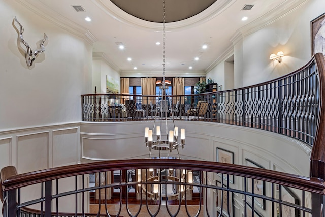 stairs with a high ceiling, crown molding, and an inviting chandelier