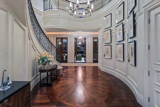 entryway with a high ceiling, parquet floors, and an inviting chandelier