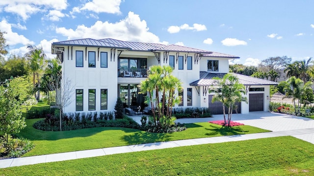 view of front of property featuring metal roof, decorative driveway, a standing seam roof, and a balcony