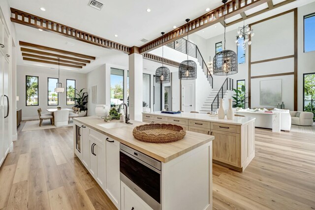 kitchen with light stone countertops, a spacious island, sink, light hardwood / wood-style flooring, and white cabinets