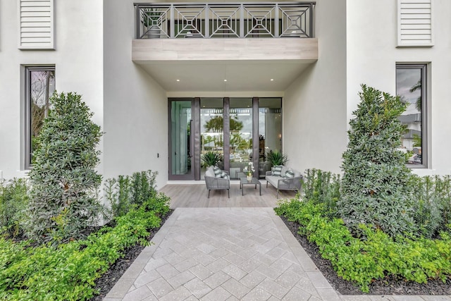 view of exterior entry with a balcony and stucco siding