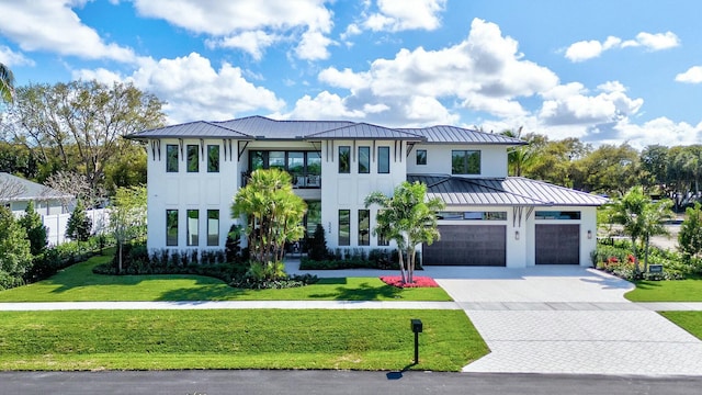 view of front of house with decorative driveway, stucco siding, a front yard, a standing seam roof, and metal roof