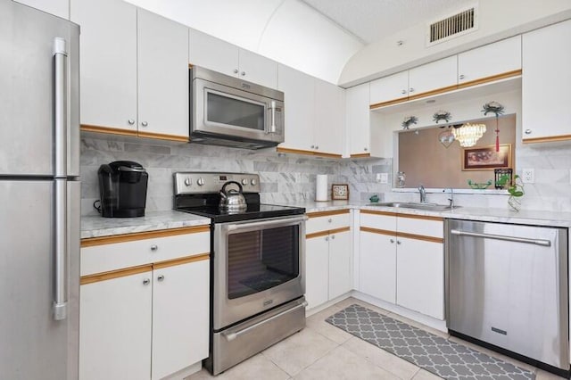 kitchen featuring stainless steel appliances, tasteful backsplash, light countertops, visible vents, and a sink