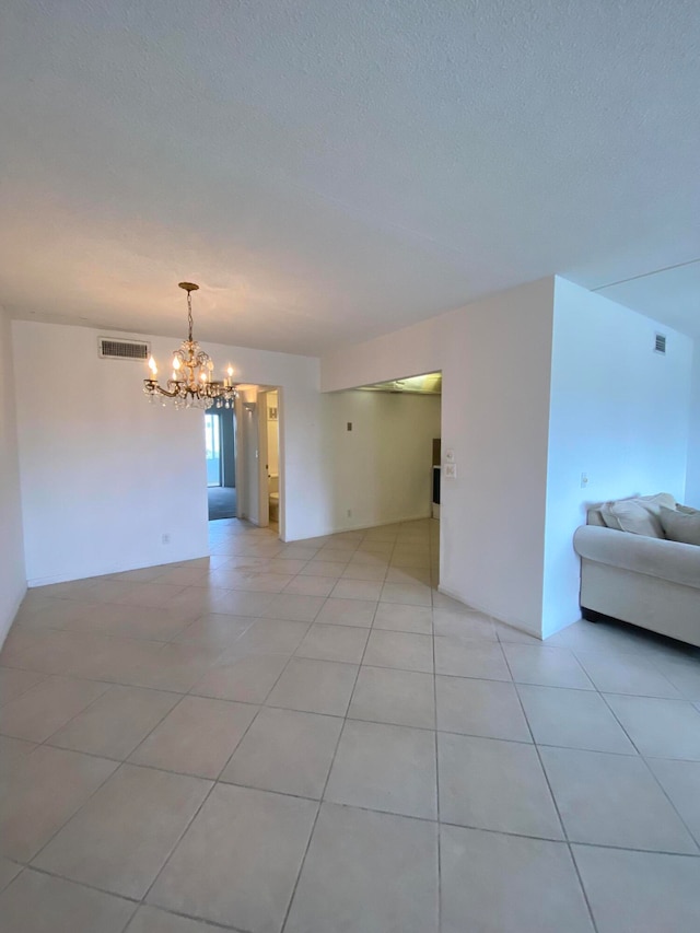 interior space featuring tile patterned flooring, a chandelier, and a textured ceiling