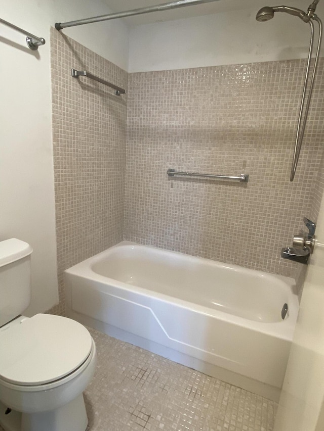 bathroom with tile patterned flooring, tiled shower / bath, and toilet