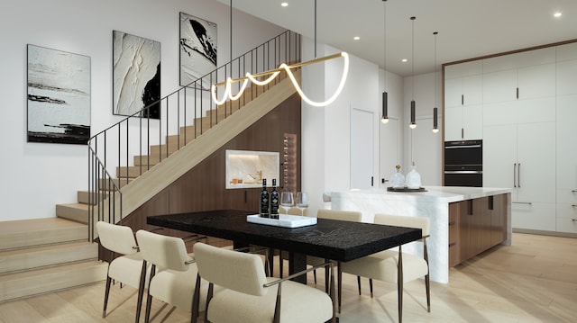 kitchen featuring black double oven, pendant lighting, white cabinetry, and light hardwood / wood-style floors