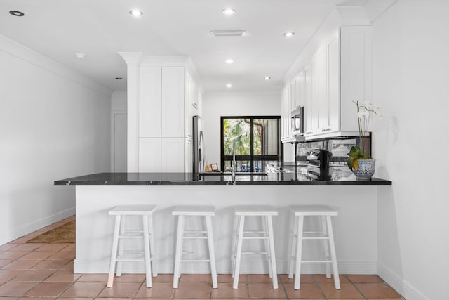 kitchen with white cabinetry, a kitchen breakfast bar, kitchen peninsula, and appliances with stainless steel finishes