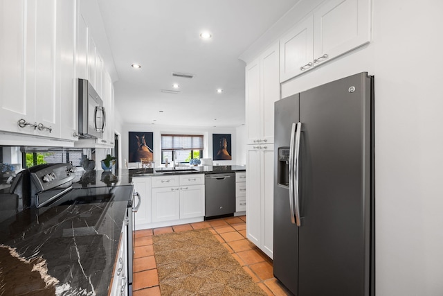 kitchen featuring white cabinetry, appliances with stainless steel finishes, light tile patterned flooring, and dark stone counters