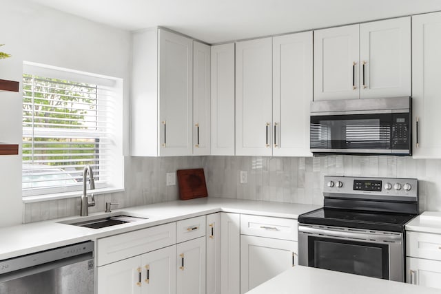 kitchen featuring appliances with stainless steel finishes, white cabinetry, sink, and tasteful backsplash