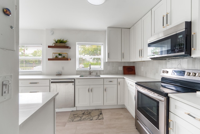 kitchen with stainless steel appliances, sink, white cabinetry, and tasteful backsplash