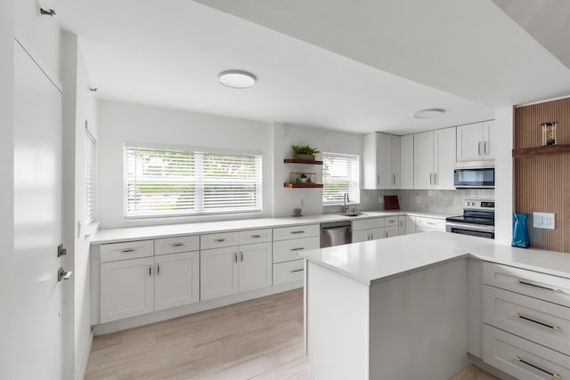 kitchen featuring light hardwood / wood-style flooring, tasteful backsplash, sink, white cabinetry, and appliances with stainless steel finishes