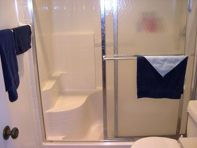 bathroom featuring toilet and a shower with door