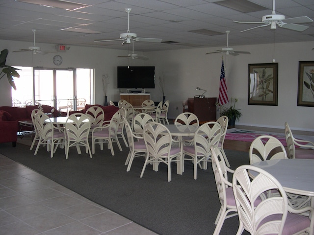 tiled dining room with ceiling fan and a drop ceiling