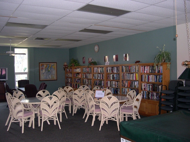 carpeted dining space with a paneled ceiling