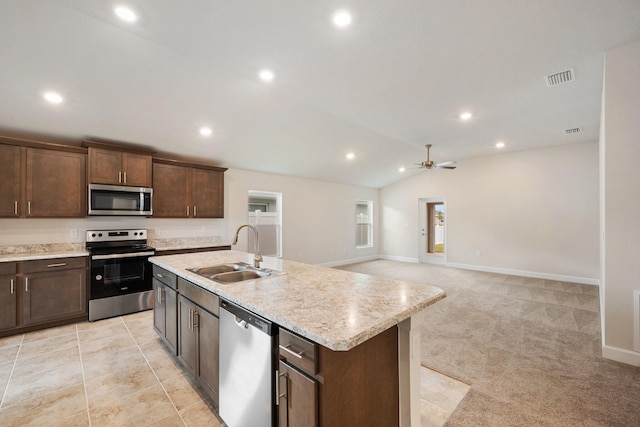 kitchen with lofted ceiling, light carpet, sink, an island with sink, and stainless steel appliances