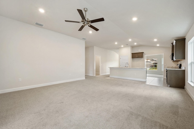 unfurnished living room featuring light carpet, sink, ceiling fan, and vaulted ceiling