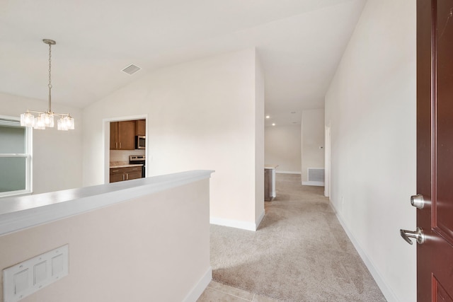 corridor featuring light carpet, a chandelier, and lofted ceiling