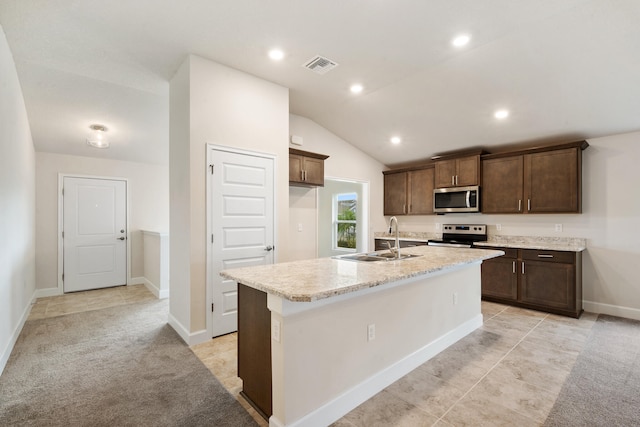 kitchen featuring light carpet, appliances with stainless steel finishes, sink, a center island with sink, and lofted ceiling