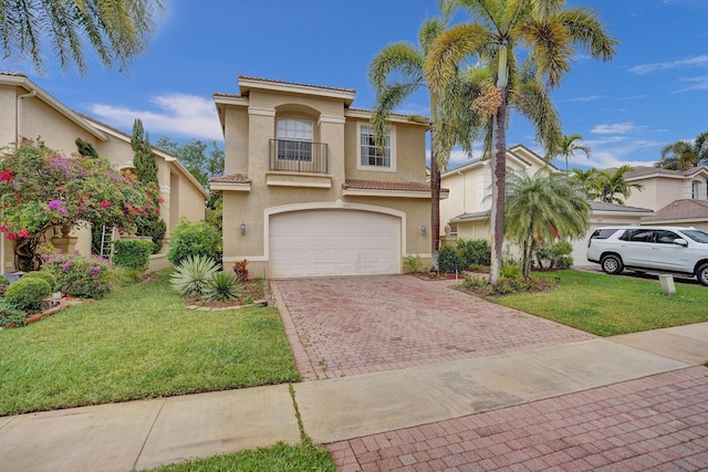 mediterranean / spanish house with decorative driveway, stucco siding, a garage, a front lawn, and a tiled roof