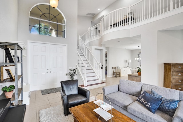 tiled living area with stairs, a high ceiling, and a chandelier