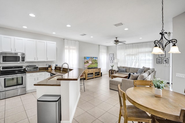 kitchen featuring stainless steel appliances, light tile patterned floors, a peninsula, recessed lighting, and a sink