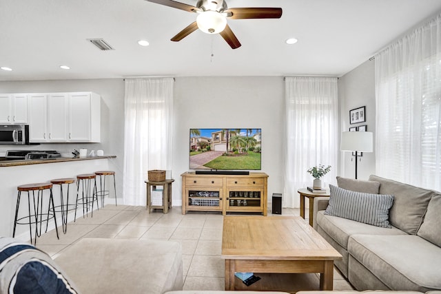 living room featuring light tile patterned floors, recessed lighting, ceiling fan, and baseboards