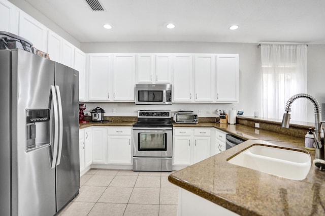 kitchen with stainless steel appliances, a sink, white cabinets, light tile patterned floors, and recessed lighting