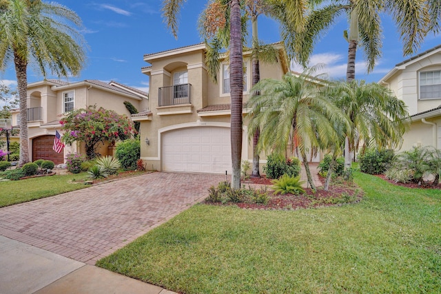 mediterranean / spanish house featuring a balcony, a garage, decorative driveway, stucco siding, and a front lawn