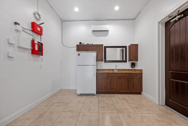 kitchen with light tile patterned flooring, sink, white fridge, and an AC wall unit