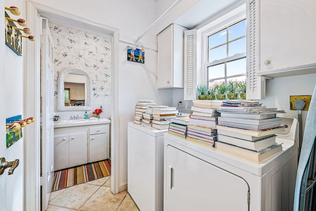 laundry area featuring washer and clothes dryer, sink, cabinets, and light tile patterned flooring