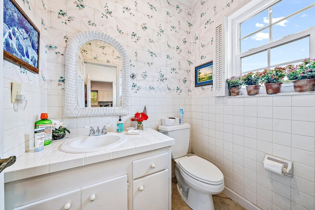 bathroom with tile patterned floors, vanity, toilet, and tile walls