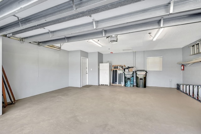 garage featuring white fridge and a garage door opener