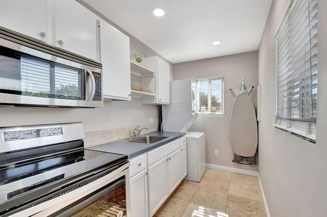 kitchen with appliances with stainless steel finishes, sink, white cabinetry, light tile patterned flooring, and stacked washer / dryer