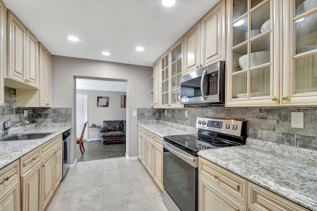 kitchen featuring sink, light stone countertops, light tile patterned flooring, decorative backsplash, and stainless steel appliances