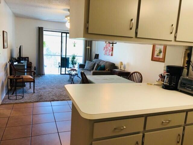 kitchen with light countertops, open floor plan, carpet flooring, tile patterned flooring, and a peninsula