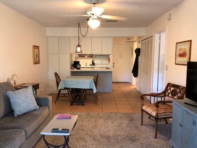 living area with a ceiling fan, visible vents, and light tile patterned floors