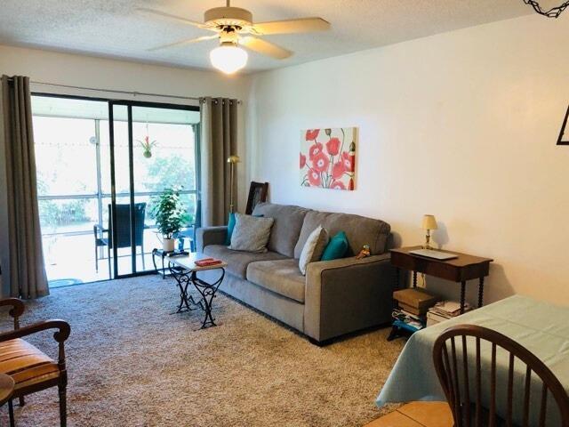 living room with ceiling fan, a textured ceiling, and carpet flooring