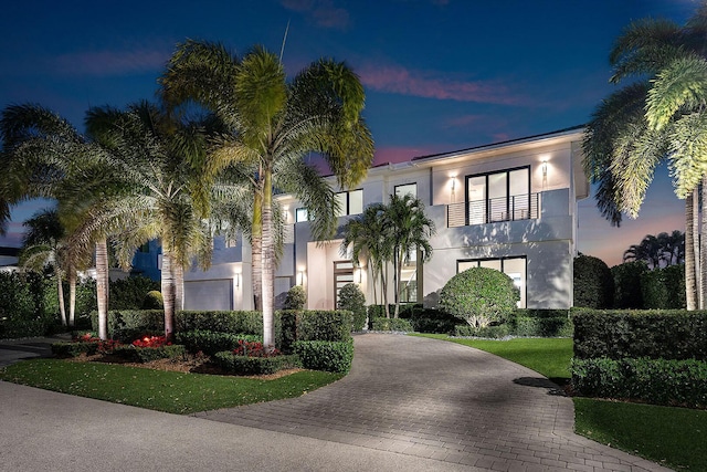 view of front of property featuring a balcony and a yard