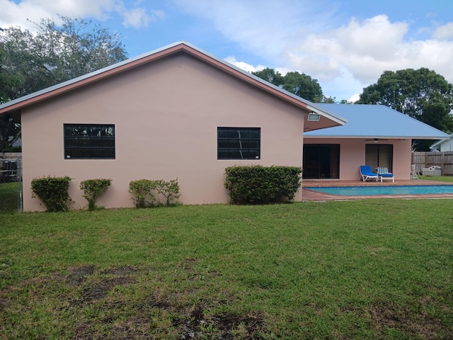 rear view of property with ceiling fan, a patio area, and a yard