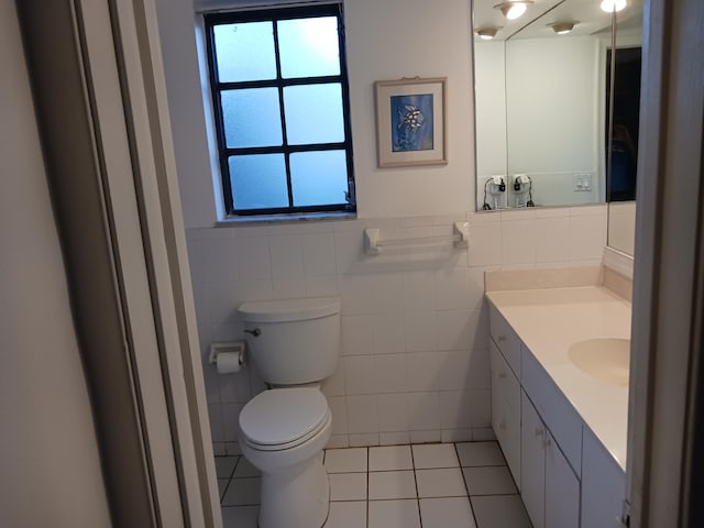 bathroom with tile patterned floors, vanity, toilet, and tile walls