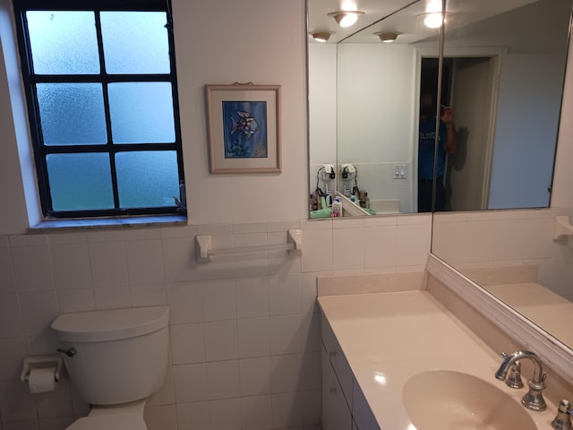 bathroom with vanity, toilet, and tile walls